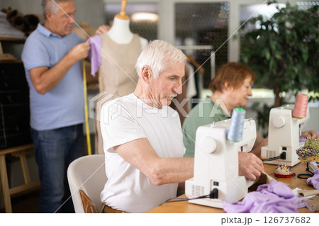 Senior man work with mannequin at sewing school studio, others people sew and talking 126737682
