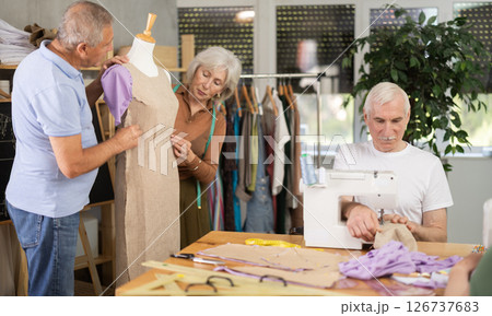 Elderly man and woman working with mannequin and sewing in class 126737683