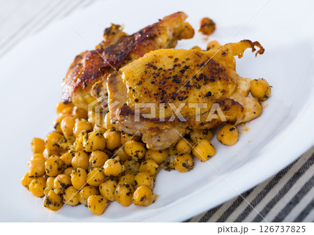 Fried chicken thighs served with garbanzo at plate on table 126737825