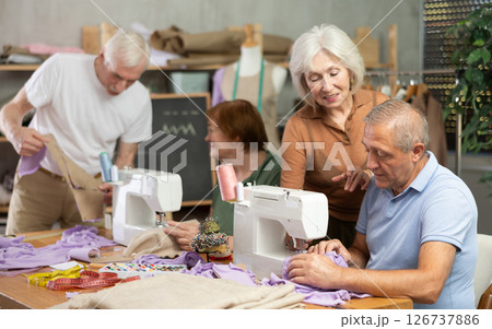 Elderly female showed group of elderly people how to sew on machine Elderly female showed group of elderly people how to sew on machine 126737886