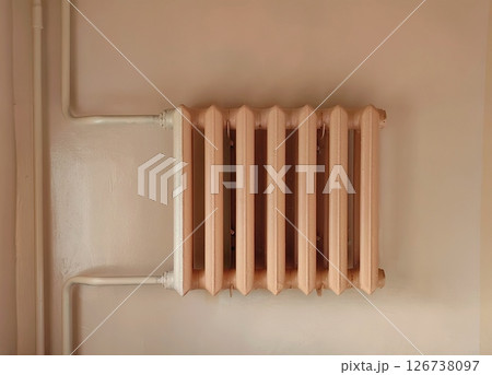 vintage radiator mounted on pale wall in an indoor setting showcasing retro heating design. closeup. vintage radiator mounted on pale wall in an indoor setting showcasing retro heating design. closeup. 126738097