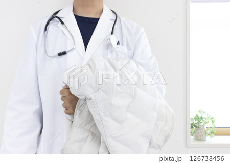 ダウンジャケットを持った医者のイメージ（日本人、男性、顔無し、30代） 126738456