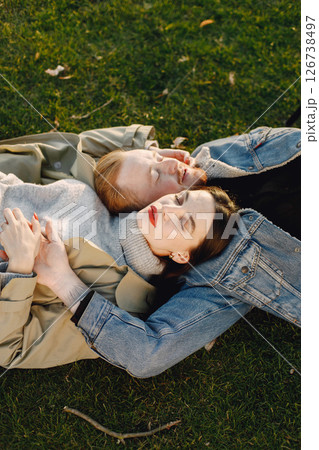 Man and woman in fashion clothes resting on a nature together. Man wearing jacket and a black hat and woman coat. Photo of romantic couple hugging. Man and woman in fashion clothes resting on a nature together. Man wearing jacket and a black hat and woman coat. Photo of romantic couple hugging. 126738497