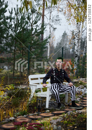 An Eccentric Individual Dressed in Striped Attire Relaxing in a Serene Garden Setting 126738832