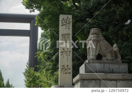 【日本】東京都千代田区の靖国神社の鳥居前に建てられ神社名が彫られた石柱と狛犬の石像 126738972