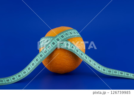 Orange wrapped with a measuring tape, representing diet and weight loss. Orange wrapped with a measuring tape, representing diet and weight loss. 126739985
