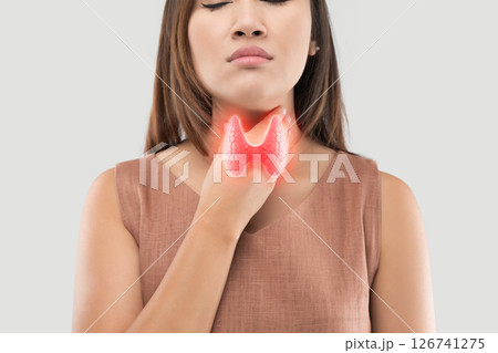 A woman holding her throat, illustrating potential thyroid pathology. 126741275