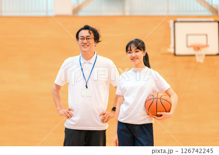 体育館にいる部活の顧問の男性教師とバスケットボールを持つ女子生徒 体育館にいる部活の顧問の男性教師とバスケットボールを持つ女子生徒 126742245