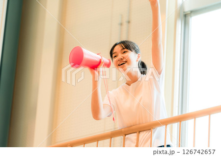 体育館でメガホンを持って応援する体操着姿の女子生徒（エール,声援,頑張れ） 126742657
