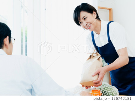 食材をテーブルに並べるホームヘルパーの女性 食材をテーブルに並べるホームヘルパーの女性 126743181