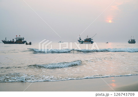 Vietnamese fishing ships and boats at sea in the morning at sunrise in a fishing village in Vietnam Vietnamese fishing ships and boats at sea in the morning at sunrise in a fishing village in Vietnam 126743709