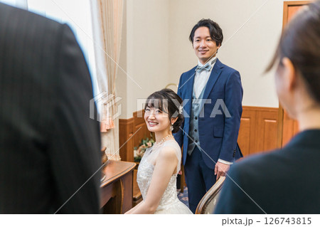 結婚式場のブライズルーム,控え室でスタッフ,支配人,父親と話す新郎新婦 結婚式場のブライズルーム,控え室でスタッフ,支配人,父親と話す新郎新婦 126743815