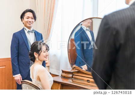結婚式場のブライズルーム,控え室でスタッフ,支配人,父親と話す新郎新婦 126743818