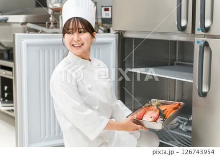 冷蔵庫から食材を取り出すコックコート姿のシェフの女性 126743954