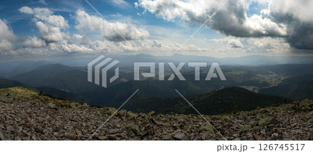 A stunning view of the mountain horizon beneath a bright blue sky dotted with clouds. A stunning view of the mountain horizon beneath a bright blue sky dotted with clouds. 126745517
