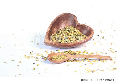 Crushed pistachio nuts in wooden bowl and heart-shaped spoon for cooking. Environmentally friendly product and health. Crushed pistachio nuts in wooden bowl and heart-shaped spoon for cooking. Environmentally friendly product and health. 126746084