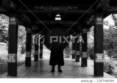 Urban Elegance: The Enigmatic Figure in a Long Coat and Umbrella 126746094