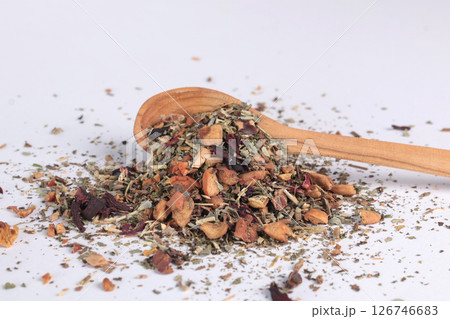 Dry green tea with pieces of fruit on wooden spoon on white background. Drinks, organic product and health. Dry green tea with pieces of fruit on wooden spoon on white background. Drinks, organic product and health. 126746683