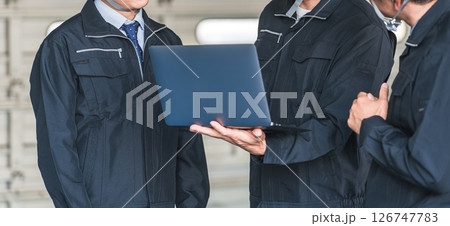 工場・倉庫・物流センターでパソコンを見ながら打ち合わせをする作業員の男性 126747783