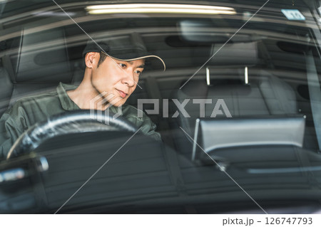 自動車の車内をチェックする自動車整備士の男性スタッフ 126747793