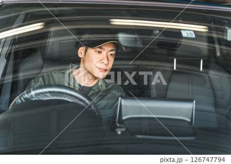 自動車の車内をチェックする自動車整備士の男性スタッフ 126747794