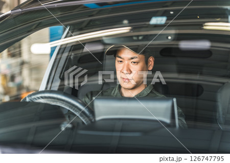 自動車の車内をチェックする自動車整備士の男性スタッフ 126747795