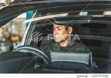 自動車の車内をチェックする自動車整備士の男性スタッフ 126747796