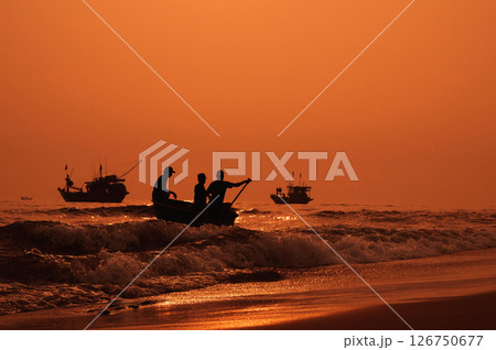 Silhouettes of Vietnamese fishermen on baskets boats and fishing ships at sea in the morning at sunrise in Vietnam Silhouettes of Vietnamese fishermen on baskets boats and fishing ships at sea in the morning at sunrise in Vietnam 126750677