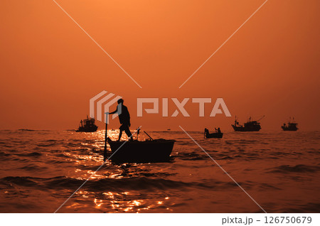 Silhouette of a Vietnamese male fisherman on round basket boat in sea in a fishing village in the morning at sunrise in Vietnam Silhouette of a Vietnamese male fisherman on round basket boat in sea in a fishing village in the morning at sunrise in Vietnam 126750679