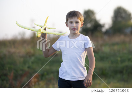 Little boy in the field plays with a yellow plane. 126751068