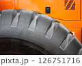 A CloseUp Image Featuring a Heavy Machinery Tire Against a Bright Orange Background 126751716