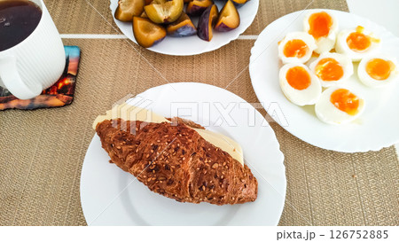 Enjoying delicious european breakfast with eggs, cheese, croissant, plums and tea in prague 126752885