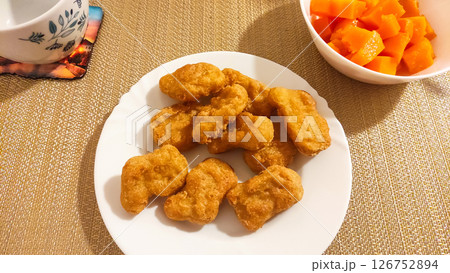 Chicken nuggets served on white plate with diced pumpkin and tea in prague 126752894