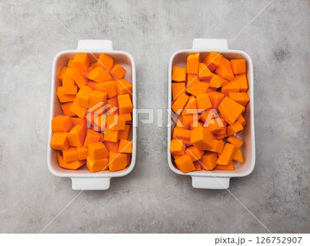 Diced butternut squash filling two white ceramic baking dishes 126752907