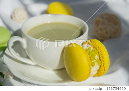 Sweet yellow macaron dessert Cup of green plant based matcha tea latte in cozy morning bed atmosphere. Creative holiday romantic date idea. Herbal prebiotic fiber superfood beverage antioxidant-rich 126754420
