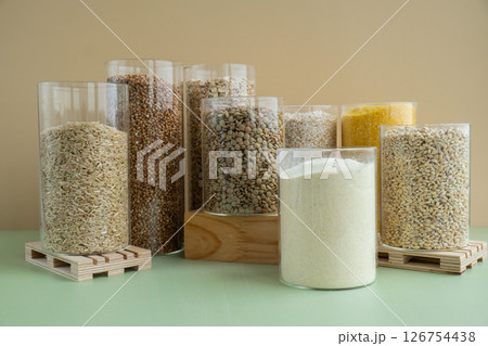 Refillable glass jar with raw grain porridge. Copy space Refill product format eco-friendly living. Filling reusable container Whole spelt grain species. High protein fiber-rich vegan plant based food 126754438