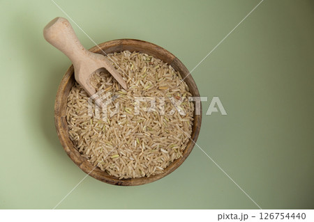 Brown rice in green background copy space. Whole spelt grain species. High protein fiber-rich vegan plant based food ingredient. Gluten free superfood healthy nutritional dietary alternative Brown rice in green background copy space. Whole spelt grain species. High protein fiber-rich vegan plant based food ingredient. Gluten free superfood healthy nutritional dietary alternative 126754440