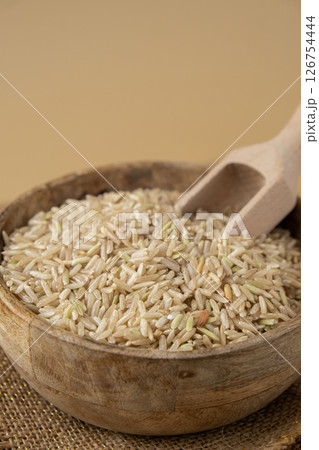 Brown rice in neutral beige background copy space. Whole spelt grain species. High protein fiber-rich vegan plant based food ingredient. Gluten free superfood healthy nutritional dietary alternative 126754444