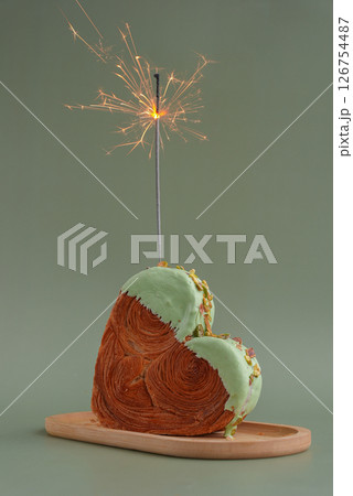 Shiny festive candle sparkler birthday celebration holiday Delightful and vibrant heartshaped pastry croissant treat, beautifully topped with colorful frosting nut galore. Mock up template copy space 126754487