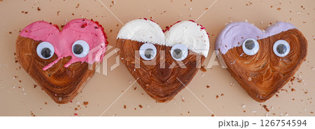 Funny food game face with crazy eyes April fool day joke Delightful and vibrant heartshaped pastry croissant treat, beautifully topped with colorful frosting galore. Food experimentation dessert 126754594