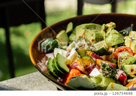 Avocado mix of vegetables salad in daytime outdoors. Fresh salad with tomatoes, avocado, lettuce onion cucumber. Healthy and detox food concept. Ketogenic diet Avocado mix of vegetables salad in daytime outdoors. Fresh salad with tomatoes, avocado, lettuce onion cucumber. Healthy and detox food concept. Ketogenic diet 126754698