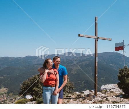 Couple Embracing by Mountain Cross with Scenic View 126754875