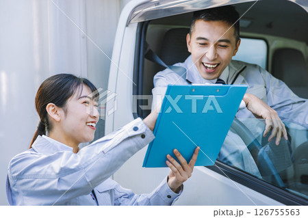 トラックのドライバーと打ち合わせをする配送スタッフ 126755563