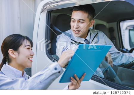 トラックのドライバーと打ち合わせをする配送スタッフ 126755573