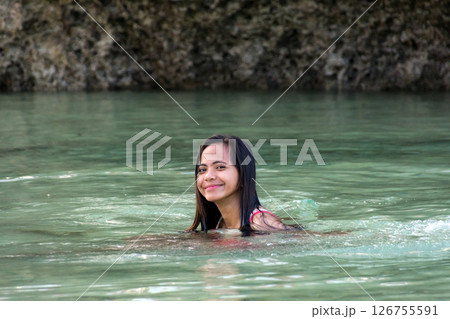 Young Asian woman swimming in tropical river with rocks behind Young Asian woman swimming in tropical river with rocks behind 126755591