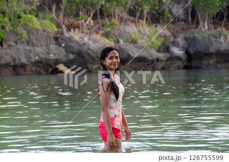 Young asian woman in swimsuit standing in tropical river with rocks behind 126755599