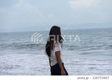 Woman standing confidently by the waves on sandy coast 126755607