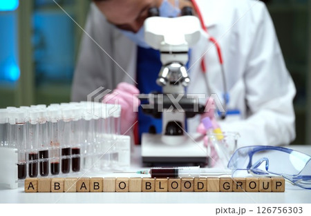 A scientist analyzes various blood groups meticulously in a lab using a microscope A scientist analyzes various blood groups meticulously in a lab using a microscope 126756303