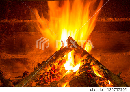burning firewood in chimney with pine cones 126757395