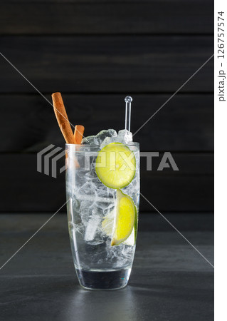 Gin tonic cocktail with lima cinnamon and ice cube on black Gin tonic cocktail with lima cinnamon and ice cube on black 126757574